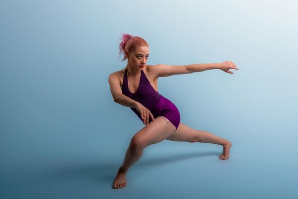 Woman performing a fluid movement exercise in a minimalist studio.